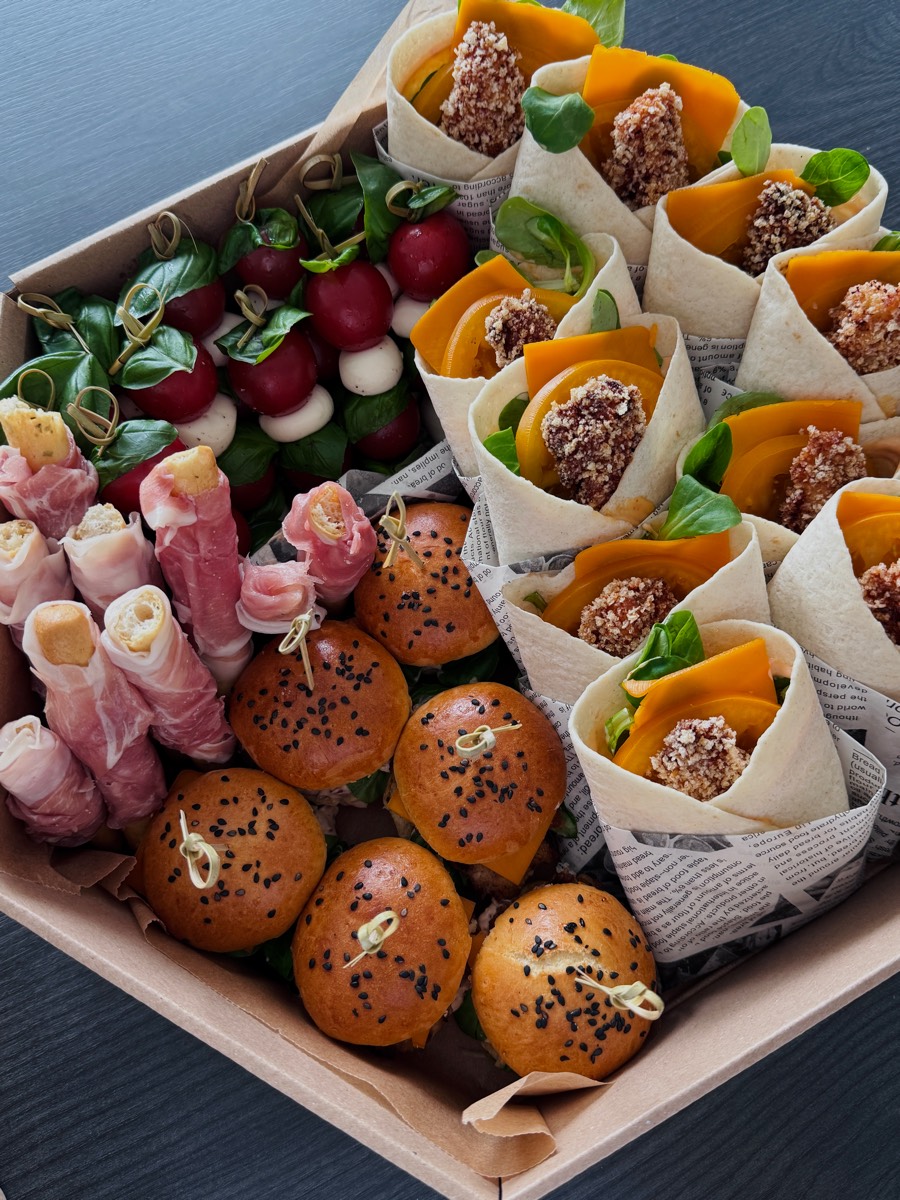 Box z mini burgerami z czarnuszką, wrapami z panierowanym kurczakiem i mango, koreczkami caprese oraz roladkami z szynki