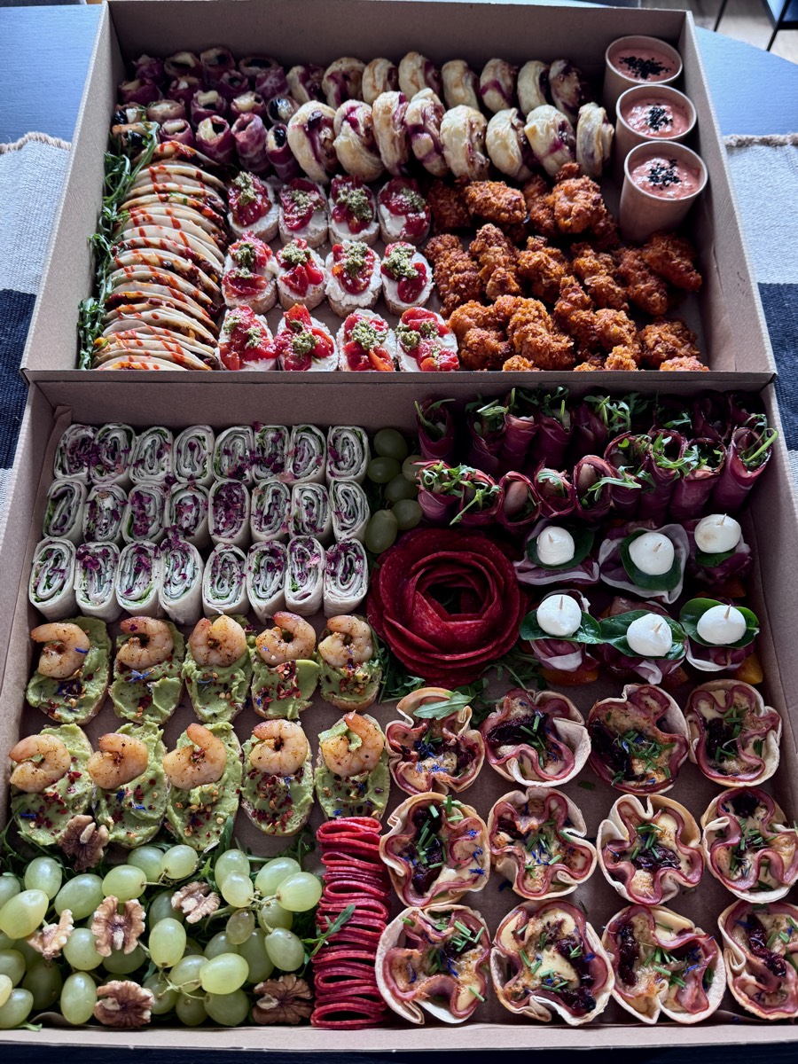 Dwa duże boxy: krewetki na guacamole, koszyczki z szynki z camembertem i żurawiną, roladki z bresaoli z rukolą, róża z salami, roladki z tortilli, nuggetsy, winogrona, orzechy